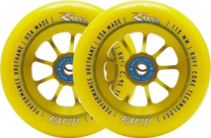 Roues River Rapid Sunrise 110 mm en jaune intense, posées de biais pour révéler le noyau à rayons et les détails du logo River. Le contraste entre la gomme brillante et l’aluminium anodisé capte la lumière, soulignant la qualité de finition.