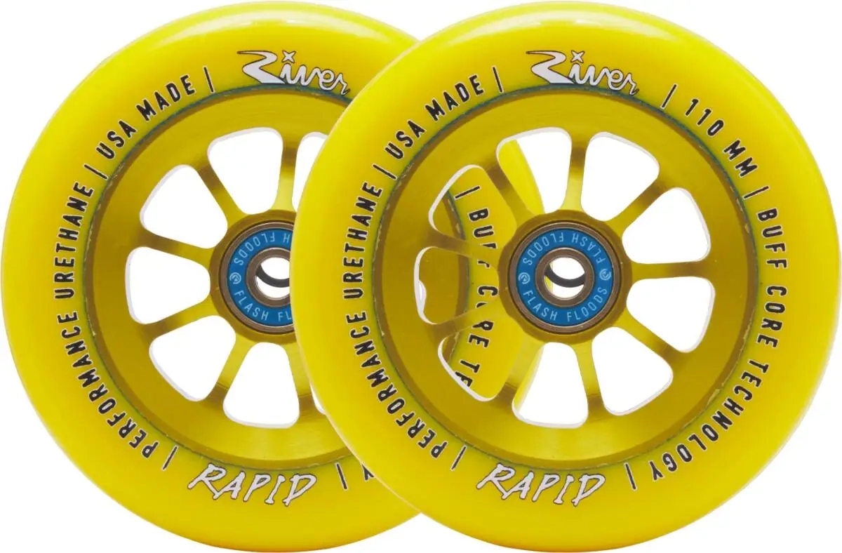 Roues River Rapid Sunrise 110 mm en jaune intense, posées de biais pour révéler le noyau à rayons et les détails du logo River. Le contraste entre la gomme brillante et l’aluminium anodisé capte la lumière, soulignant la qualité de finition.